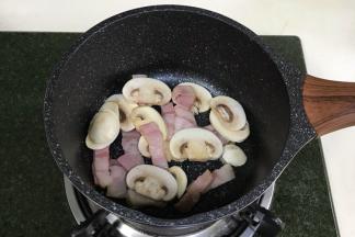 开火，锅中倒入橄榄油，放入培根和口蘑翻炒至微微变色。