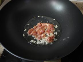 锅烧热，然后加入花生油，把切碎的大蒜放进去爆出香味，接着把腌制好的猪肉末放进去煸炒。