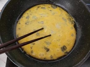 准备一锅不粘锅，加入一勺植物油，然后倒入蛋液，一边倒，一边用筷子不停搅散。