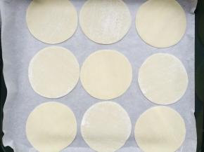 饺子皮平铺在铺上油纸的烤盘上。