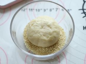 汉堡胚表面喷少许水，圴匀地沾上熟白芝麻。