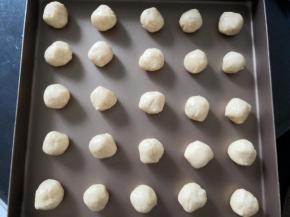 手戴一次性硅胶手套，将面团平均分成50份，搓圆，摆入两个烤盘