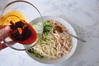 将面条捞出，把黄瓜丝、鸡丝放入，倒入调好的调味料即可。