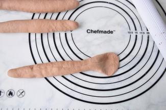 将面团搓至约25cm长，用擀面杖压扁一头。