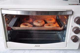 将煮好的贝果沥去水分，排在烤盘上，放入预热至200度的烤箱中层，上下火，烘焙20分钟。注意，烤箱一定要提前预热，贝果从锅中捞出一定要马上烘烤。每个烤箱的脾气都不同，我用的是北美电器ACA电烤箱，您可以根据自家烤箱的实际情况调整一下用时和温度。