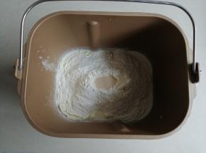 把牛奶、蛋液、糖和盐都倒入面包桶内，再倒入奶粉和面粉，在面粉顶端加入酵母