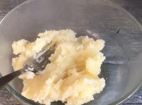 取出蒸熟的土豆片，倒入大点的容器内，压成泥状