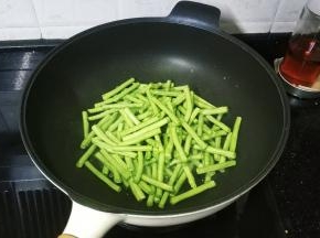 锅里热油高涨时倒入沥干水分的豆角段
