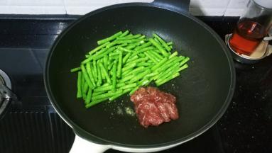将豆角推锅边，放入牛肉片