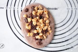 将面团擀成椭圆或长方型，放入核桃和葡萄干馅。