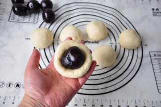 将面团轻轻按扁， 取40克馅料放入。馅料我们可以提前团成形状，这更容易包。