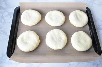 一定要注意，包好后， 收口要向朝下放置，如果用的是不粘烤盘，可以直接放置，如果是普通烤盘，请铺油纸或油布。 然后将面包体轻轻下压成圆饼。面饼尽可能的压扁一些，这样烤制出来会更好看