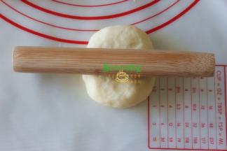 取一块面团压扁，千万不要再揉了。用擀面杖从面团的中间往上擀，接着往下擀，形成椭圆形。