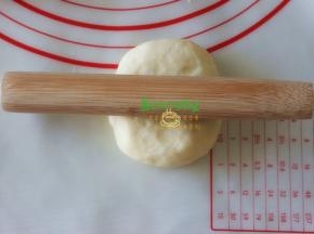 取一块面团压扁，千万不要再揉了。用擀面杖从面团的中间往上擀，接着往下擀，形成椭圆形。