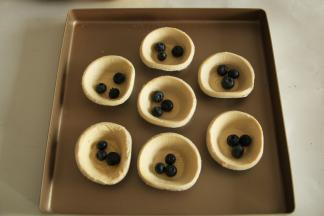 蛋挞皮中，先放入清洗干净的蓝莓。随意放，看个人喜好。3-5粒都可以。