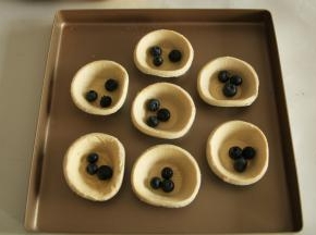 蛋挞皮中，先放入清洗干净的蓝莓。随意放，看个人喜好。3-5粒都可以。