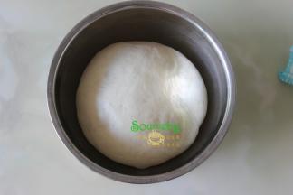 从厨师机的桶取出面团揉至光滑，放入一个大盘子里，盖上一块湿布，让其发酵变大原来的2倍。