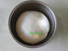 从厨师机的桶取出面团揉至光滑，放入一个大盘子里，盖上一块湿布，让其发酵变大原来的2倍。