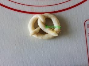 将两头往下翻过来，粘在圆圈底部，这种饼干的面团非常软，建议扭好的饼干胚，直接在烤盘上，比在擀面台上要省事。