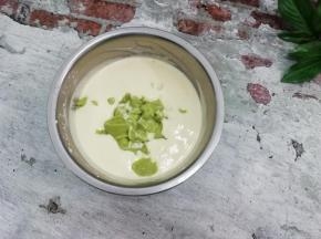 在把打好的牛油果泥倒入奶油中拌均匀