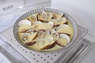 因为蒸锅的盖子是透明的，所以可以随时观察鸡蛋的成熟度，大约八分钟后，蛋液凝固，就可以关火了，这里要提醒大家，如果想省时省火，建议您用我这种大深盘，这种盘容量大，倒入蛋液后可以不完全没过文蛤，而且越大的盘，蛋液与锅的接触面越大，更容易蒸熟。