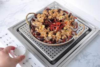 将炒好的蒜蓉调料，均匀的浇在小龙虾表层。然后放入蒸箱中。这个臻米电蒸箱10秒即可出热气，非常的方便。如果您是用普通蒸锅也可以，蒸制时间要控制在七至八分钟左右即可。这个锅因为是透明的，所以更能直接的看到里面虾蒸制的状态。