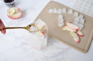 找一个杯子，先在底部放入几片桃子，然后加入冰块。