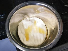 20分钟后拿开湿布，倒入2勺子油，将面团揉至光滑