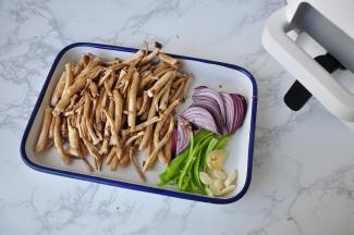 首先打开烹饪机的手机APP程序，搜到自己需要制作的菜。如果在菜单中没有我们想要做的，我们可以通过寻找类同的菜谱来操作。我选的是干锅茶树菇。然后准备好食材。将茶树菇去掉老根，然后仔细清洗，茶树菇在清洗的过程中，伞盖都碎了，所以只剩下菌杆了，将蒜姜切片，洋葱青椒切丝备用。