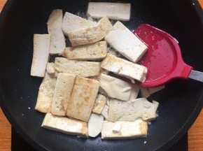 豆腐表面撒上少许盐，使豆腐更入味，并不时晃动煎锅使豆腐受热均匀；