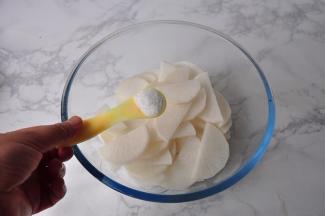 将萝卜片放在容器中，加入盐抓匀，大约腌制半小时左右。