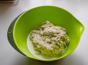 倒入面筋粉，边倒入边用筷子搅拌，避免面粉结疙瘩，出现面疙瘩就用手搅散捏开。面粉吸足水分后变成粗拉拉的面团，盆里有多余的水，直接倒掉就好。
