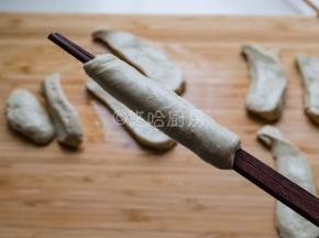 用一双筷子先夹住面筋的一头，一手拉伸拉长面团，一手转动筷子，让面团斜着缠绕在筷子上，最后的面团要抻开抻薄包裹住筷子上的面团，最后就是图中的样子。面团最后不抻薄也可以，直接缠绕就行。