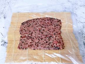 将席卷上铺上一张保鲜膜，放上血糯米，压平整。