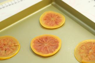 取5片沥干水分的西柚片，放在摆好油纸的28x28的方形烤盘内。​