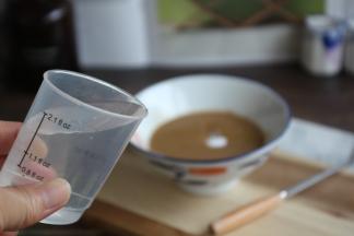 用100g的矿泉水分批分次加入到芝麻酱里，并且每加一次水就要把它搅拌均匀。