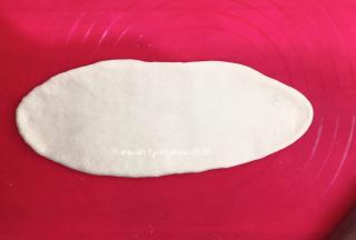 取一个小面团，把小面团擀成椭圆形，借助刮板把面团翻面