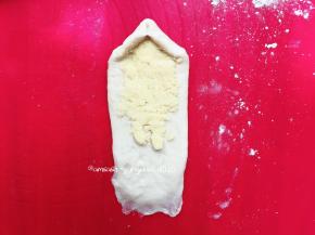 把一头的面团按压薄，这样有利于收口，然后取出椰蓉，把椰蓉平铺在面团上