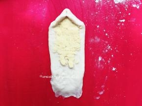 把一头的面团按压薄，这样有利于收口，然后取出椰蓉，把椰蓉平铺在面团上