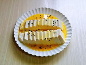 将打散的蛋液倒入盘中，再撒上黑芝麻。