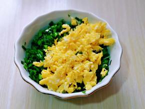 切好的韭菜放入器具中，首先加入一勺食用油，搅拌均匀，再把铲碎的鸡蛋加入韭菜器具中，搅拌均匀。