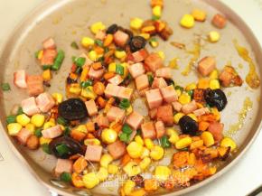 倒入玉米粒、午餐肉和香菇酱、香葱，翻炒至熟透。