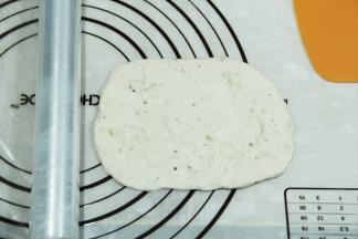 取一松弛好的面团，按扁，然后用擀面杖擀开，翻面整理成长方形。