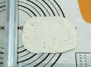 取一松弛好的面团，按扁，然后用擀面杖擀开，翻面整理成长方形。