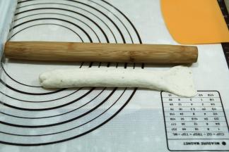 压薄底边，从上往下卷起，捏紧接口。然后将卷好的面团，来回搓长，借口朝上，22公分左右。右侧尾部擀开。
