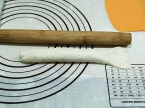 压薄底边，从上往下卷起，捏紧接口。然后将卷好的面团，来回搓长，借口朝上，22公分左右。右侧尾部擀开。