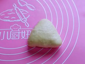 取一块面团，捏成三角形，收口捏紧，将收口朝，稍作整形。