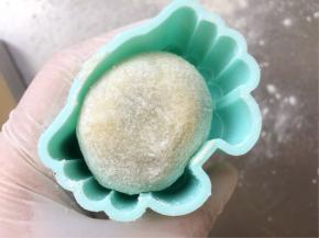 模具里扫一层薄薄的干粉，把面团也滚一层薄薄的干粉，放入