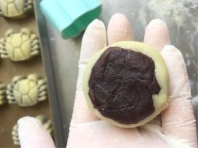 取一个饼皮包入一颗豆沙，用包汤圆的手法慢慢用虎口推着包圆即可