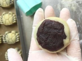 取一个饼皮包入一颗豆沙，用包汤圆的手法慢慢用虎口推着包圆即可